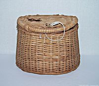 Front view of small vintage woven wicker fishing basket showing shape and latch.