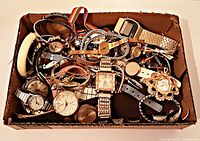 Box containing approximately 45 vintage wristwatches of various styles, sizes, and band materials piled together, showing diversity in design and condition.