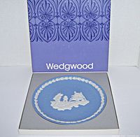 Blue Wedgwood jasperware plate with white relief of Apollo 11 moon landing scene, in original box; plate approx 8 inches diameter, box approx 9.75 inches square