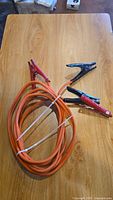 Full view of the booster cables coiled, showing red and black clamps and orange cable
