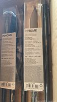 Photo showing close-up of two INHOME curtain rods in original packaging with detailed labels and product specifications, adjustable length 63-118 inches.