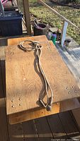 Top view of the plywood dolly showing the wood surface and the coiled rope on top