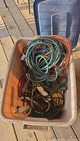 Top view of plastic container filled with assorted extension cords in various colors and power bars.