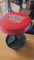 Red padded round seat with 'Torin BIG RED' logo on top of a black rolling stool base.