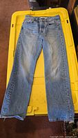Front view of girls Levi's red tab jeans, size W24 L26, laid flat on yellow storage tote.