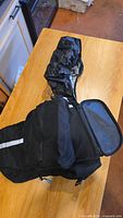 Black Raleigh bicycle travel bag displayed open to show compartments and attached rain cover.