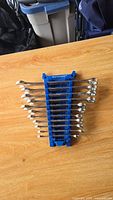 Top-down view of Mastercraft metric wrench set arranged in a blue plastic holder on wooden surface.