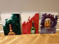 Set of three acrylic paintings showing bar-themed subjects including a bottle neck, a green wine bottle, and a beer mug, all signed by Lindsay Millikin.