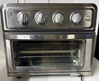 Front view of Cuisinart stainless steel toaster oven showing the four control knobs and glass door with handle.