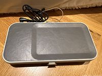 Closed Orbitkey Nest desk organizer with leather surface and USB-C cable placed on top, shown on wooden floor.