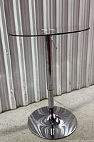 Full view side angle of the adjustable height bar table showing the glass top and chrome base.