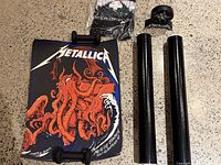 Image showing two Metallica posters with red kraken design, two poster tubes, and a Metallica branded black clock.