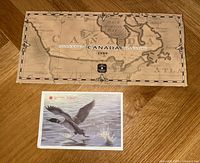 Closed packaging of the 1999 Canadian Millennium Coin Set showing a vintage map of Canada and a postcard featuring a flying loon.