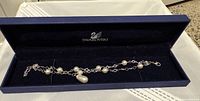 Rhodium plated double strand Swarovski bracelet with faux pearls and teardrop charm shown in Swarovski box.
