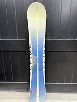 Full view of the Volk Splitn snowboard showing the top surface and gradient blue to white color with central stripe and logo.