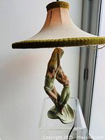 Mid century chalkware lamp with two dancer figures and fabric shade with olive green chenille trim