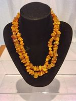 Two orange amber coral bead necklaces displayed on a black bust showing their length and bead texture.
