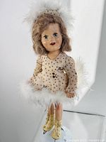 Front view of antique Barbara Ann Scott skating doll with feather trimmed dress, boots with blades, and working blue eyes.