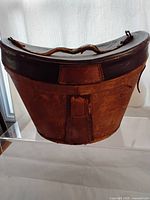 Front view of antique Victorian leather travel hat box showing worn leather exterior, handle, and leather strap details.
