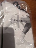 Packaged white Calvin Klein athletic socks showing branding on package and sock cuff.
