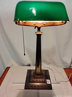 Front view showing green glass shade, brass-plated metal column and square base