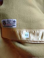 Close-up showing the Marquise brand label, indicating fine merino wool, waterproofed, pure new wool, made in England, along with a size tag showing 63 (likely lot or inventory number).