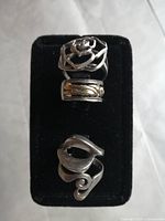 Top view of three sterling silver rings on black velvet display, showing their openwork and textured designs.