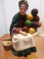 Front view of the Royal Doulton figurine showing the elderly woman holding colorful balloons and a basket attached to her side.