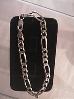 Sterling silver bracelet on black padded display stand, showing full length and clasp.