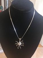 Front view of sterling silver octopus pendant on snake chain displayed on black jewelry bust, showing intricate tentacle details and pendant size.