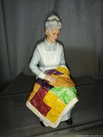 Full frontal and angled view of the Royal Doulton Eventide figurine showing the seated older woman with a quilt.