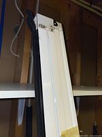 Close-up view of top labeled section of white metal accordion door frame.