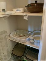 Shelf with multiple glass Pyrex and Corningware dishes including 9x13 rectangular dish, round dishes, and casseroles with lids.