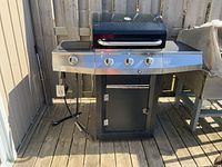 Full view of the large black and stainless steel Cuisinart barbecue grill with four control knobs and a thermometer in the lid.