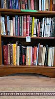 Bookshelves filled with a mix of hardcover and softcover books in various genres such as law, art, history, and fiction. Some books have worn dust jackets and visible signs of use.