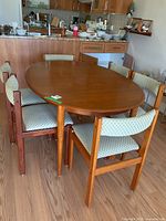 Full view of oval teak table and six chairs in dining area
