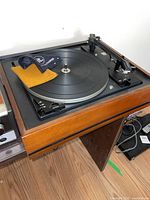 Full view of Dual 1210 turntable mounted in wood base with platter and tonearm visible.