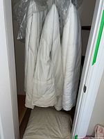 Three quilted off-white duvets hanging, two protected by white covers