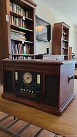 Front and angled side view showing wood cabinet with speaker grills, control panel with dial and buttons