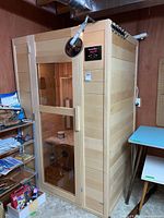 Full front view of wooden sauna unit with glass door and overhead light