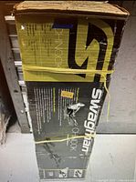 Box of Swagman Chinook hitch mount bike rack with visible wear and damage on the packaging.