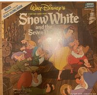 Cover of the Snow White and the Seven Dwarfs storybook with seven dwarfs around Snow White, vintage design.