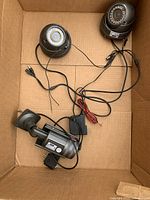 Three security cameras in cardboard box, two dome cameras and one bullet camera with wiring attached.