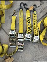 Four yellow Erickson ratchet straps with metal ratchets and vinyl coated hooks laid side by side on the ground showing the ratchet mechanisms and hook ends.
