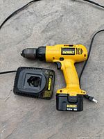 DeWalt 12 volt cordless drill and charger on concrete surface showing full drill and charger unit