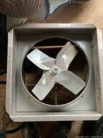 Overhead photo of the industrial fan showing square metal housing and four metal blades.