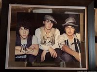 Framed color photo of the Jonas Brothers with signatures.