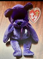 Front view of the purple Princess Diana bear showing deep purple plush, embroidered white rose on chest, and Ty heart-shaped swing tag.