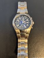 Front view of the Seiko chronograph watch showing the blue dial with three sub-dials, date window, and stainless steel bracelet.