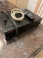 Front and top angled view of Rogers HD PVR digital cable box with remote and cable on top.